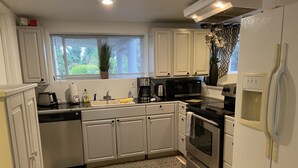 A modern kitchen with white cabinets, a stainless steel refrigerator, a microwave, and an oven. - Cozy 1 bedroom apartment, near Seattle & Airport. (Normandy Park)