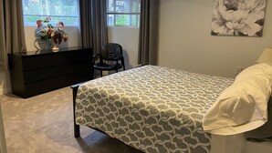 A bedroom with a bed, a dresser, a chair, and a window with curtains. - Cozy 1 bedroom apartment, near Seattle & Airport. (Normandy Park)