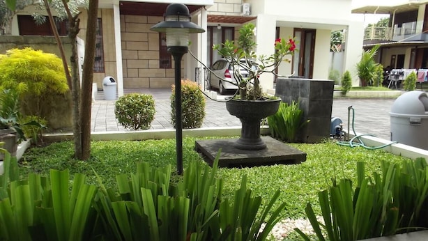 A well-maintained garden with a variety of plants, a decorative lamp, and a water feature. - Omah Dixy Family Homestay by FH Stay (Baturetno)