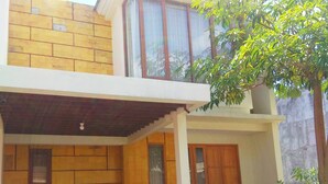 A two-story building with a yellow brick facade, large windows, and a covered entrance area. - Omah Dixy Family Homestay by FH Stay (Baturetno)