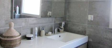 Un baño moderno con un espejo grande, un lavamanos blanco y un perchero para toallas.