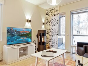 Un salon moderne doté d’un téléviseur à écran plat, d’une cheminée et d’une grande fenêtre.