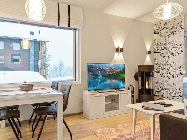 Un salon moderne doté d’un téléviseur à écran plat, d’une cheminée et d’un coin repas offrant une vue sur l’extérieur.