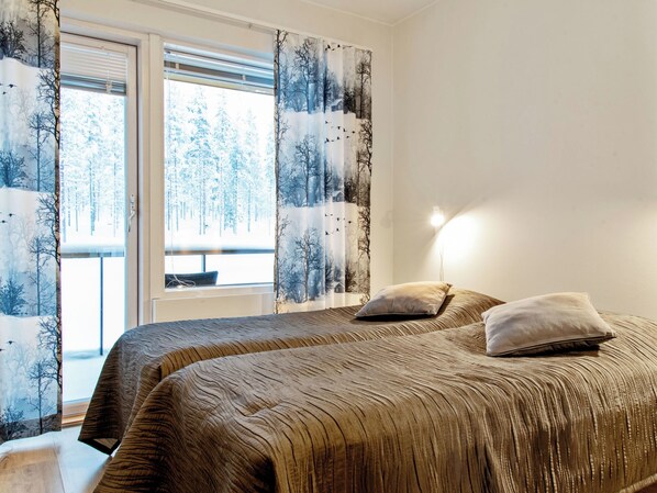 Une chambre avec deux lits, une fenêtre avec des rideaux et une lampe de chevet.