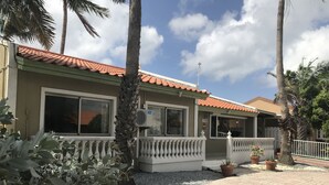 Um edifício de dois andares com telhado de telhas vermelhas, janelas amplas e uma varanda branca.