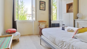 Een slaapkamer met een bed, een stoel, een raam en een radiator.