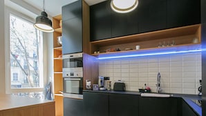 Een moderne keuken met donkere kastjes, een betegelde spatwand en een ingebouwde oven.