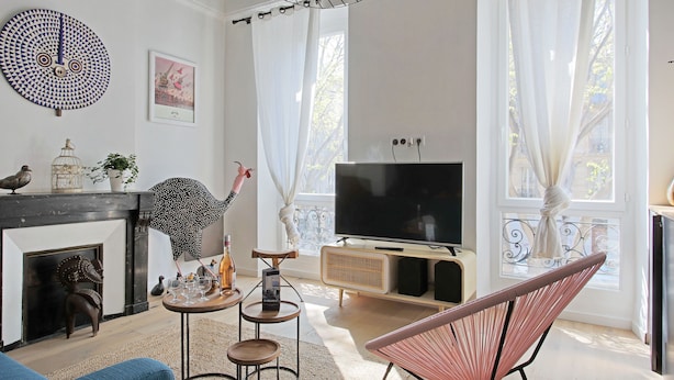 Een moderne woonkamer met een open haard, een televisie en een groot raam met gordijnen.