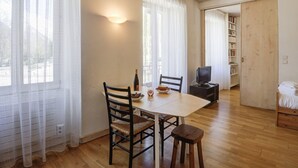 A dining area with a wooden table, chairs, a television, and a bookshelf.