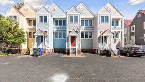 Une rangée de maisons de ville avec une entrée centrale, un espace de stationnement et une voiture garée sur le côté.