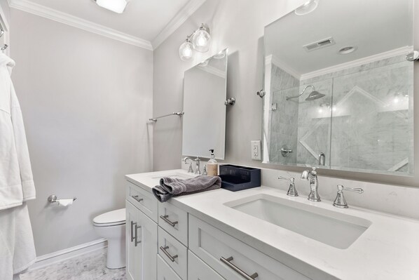 A modern bathroom with a large mirror, two sinks, and a shower.