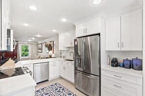 A modern kitchen with white cabinetry, stainless steel appliances, and a blue patterned rug. - Modern and Spacious home with a fantastic, central, downtown location (Charleston)
