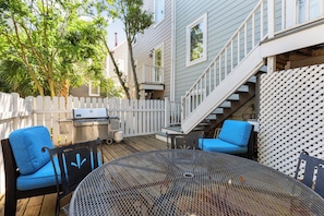 Une terrasse dotée de mobilier d’extérieur, d’un barbecue et d’un escalier menant à un deuxième niveau.
