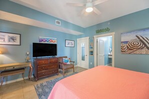 Un dormitorio con una cama, un aparador, un televisor y una puerta que da a un baño.