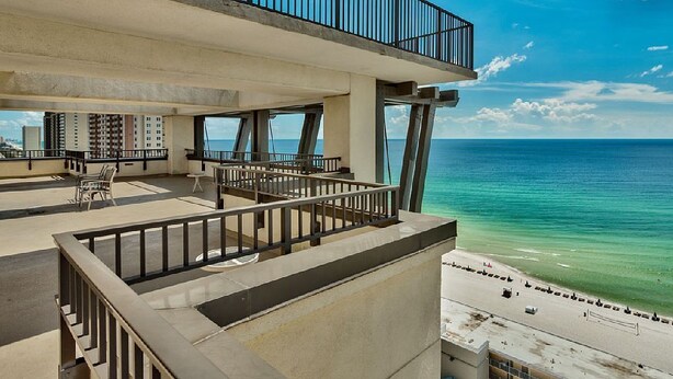 Un edificio alto con un balcón que da a la playa.