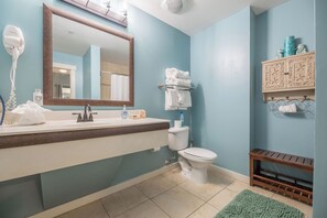 Un baño con lavamanos, espejo, inodoro y toallero.