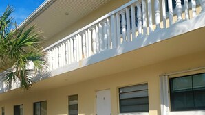 A two-story building with a balcony, a door, and windows.