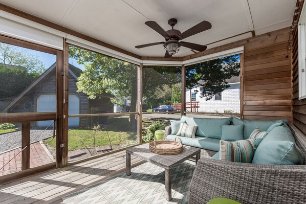 A covered patio with a ceiling fan, wicker furniture, and a view of the backyard.
