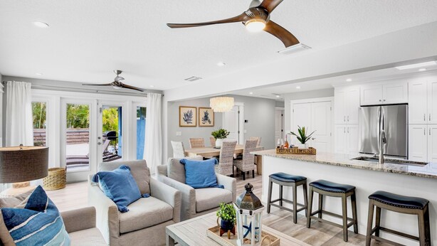 A modern kitchen with white cabinets, stainless steel appliances, and a bar area with stools. - Blue Oasis West:  Private Pool & Spa | 2 King Beds | 5-Min Walk to Beach (Holmes Beach)