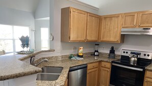 A modern kitchen with granite countertops, stainless steel appliances, wooden cabinets, and a dishwasher. - Lovely ❤️ Beach style Apt near Disney & Universal (Kissimmee)