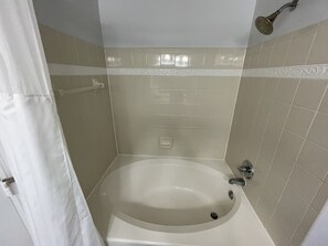 Een bad/douchecombinatie, een haardroger, handdoeken, zeep
