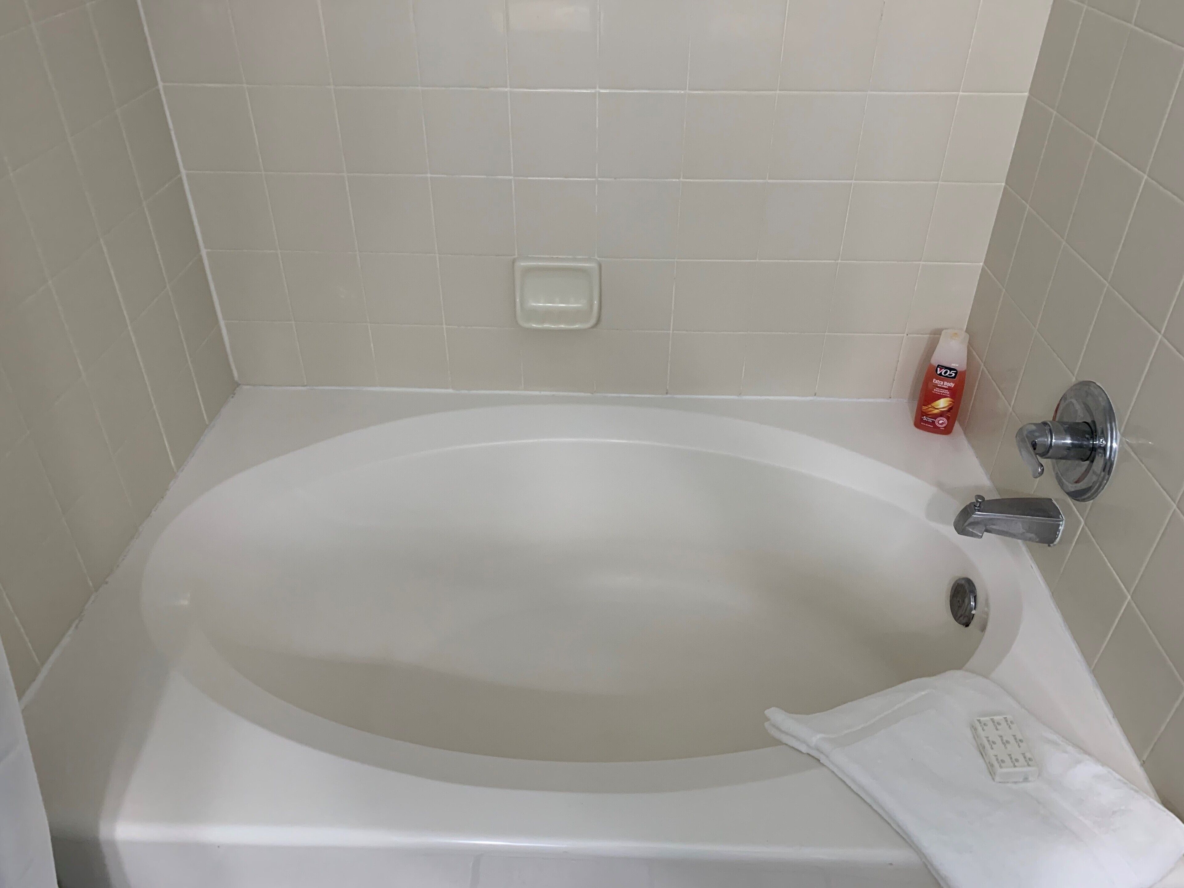 A white bathtub with a chrome faucet and a soap dish on the wall.