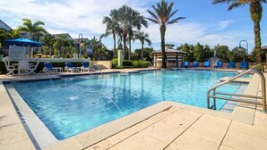 A swimming pool with blue water, surrounded by palm trees and lounge chairs. - Lovely ❤️ Beach style Apt near Disney & Universal (Kissimmee)