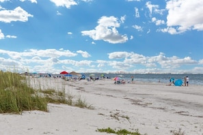 A beach with people, umbrellas, and tents.
