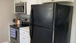 A kitchen with white cabinets, a black refrigerator, a microwave, and a stove. - Beautiful 3 Bed, 2 Bath, Sleeps 6, Full Kitchen. garage. Close to World cup! (Lee's Summit)