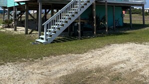 A two-story house with a balcony and a staircase leading to the second floor. - Gulf and Bay Views in Fort Morgan! Short walk to beach. Room to park the boat! (Gulf Shores)