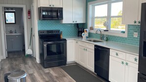 A modern kitchen with white cabinets, a black stove, and a microwave. - Gulf and Bay Views in Fort Morgan! Short walk to beach. Room to park the boat! (Gulf Shores)