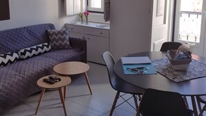 Ett modernt vardagsrum med en soffa, två små bord och ett matbord med stolar.