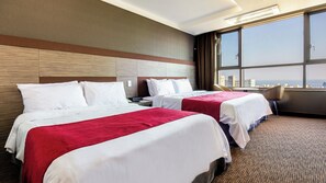 A hotel room with two beds, a large window, and a city view. - Shin Shin Hotel Jeju Eastern (Seogwipo)