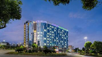 A modern hotel with a glass facade, multiple floors, and a well-lit entrance.