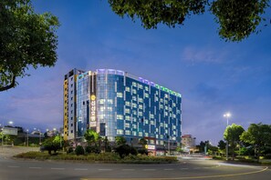 A modern hotel with a glass facade, multiple floors, and a well-lit entrance. - Shin Shin Hotel Jeju Eastern (Seogwipo)