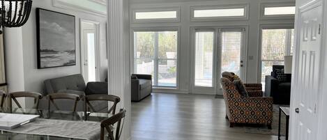 A spacious living room with a dining area, large windows, and a view of the outdoors.
