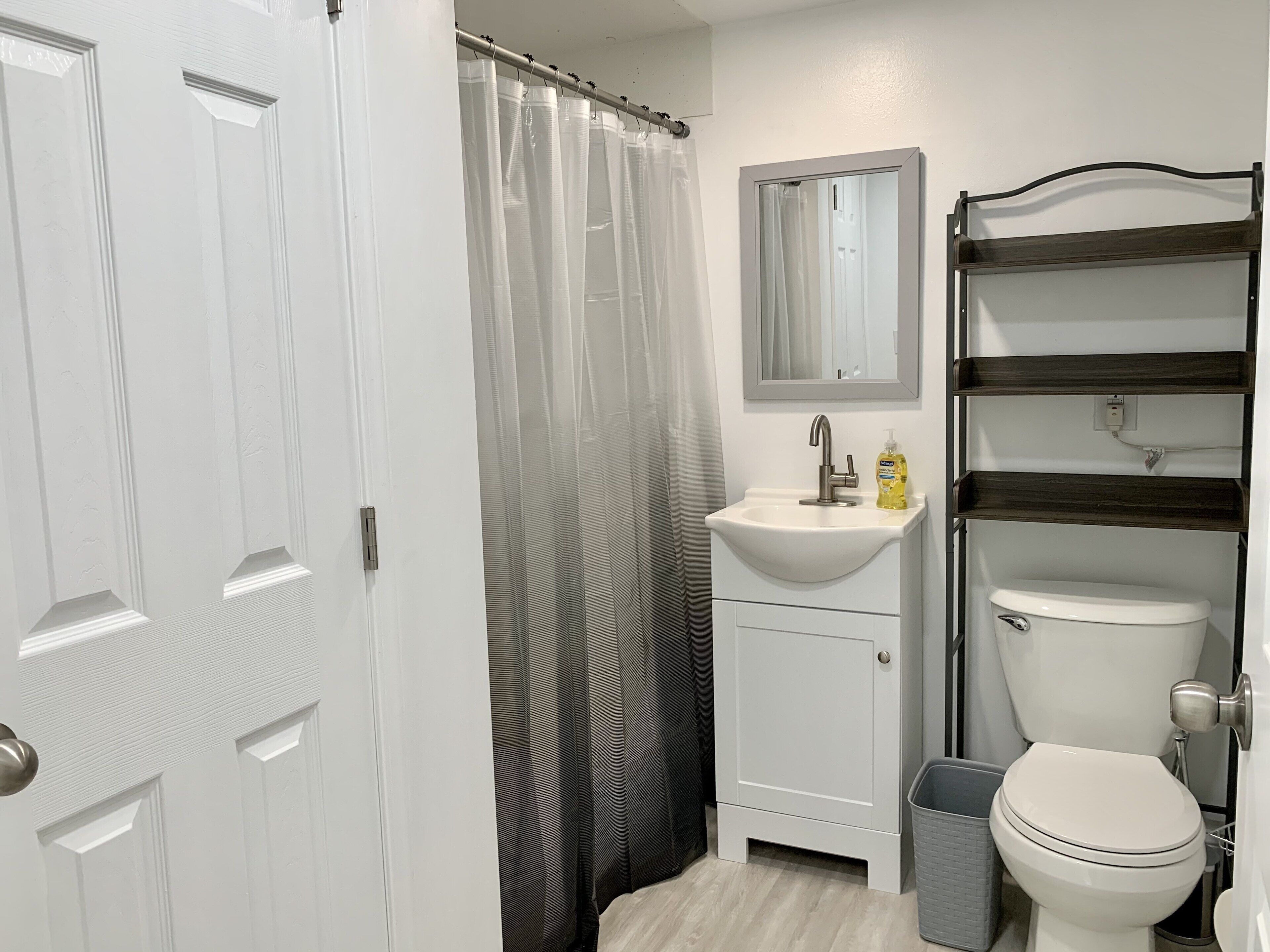 A bathroom with a white sink, a mirror, a toilet, and a shower curtain.