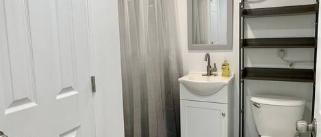 A bathroom with a white sink, a mirror, a toilet, and a shower curtain.