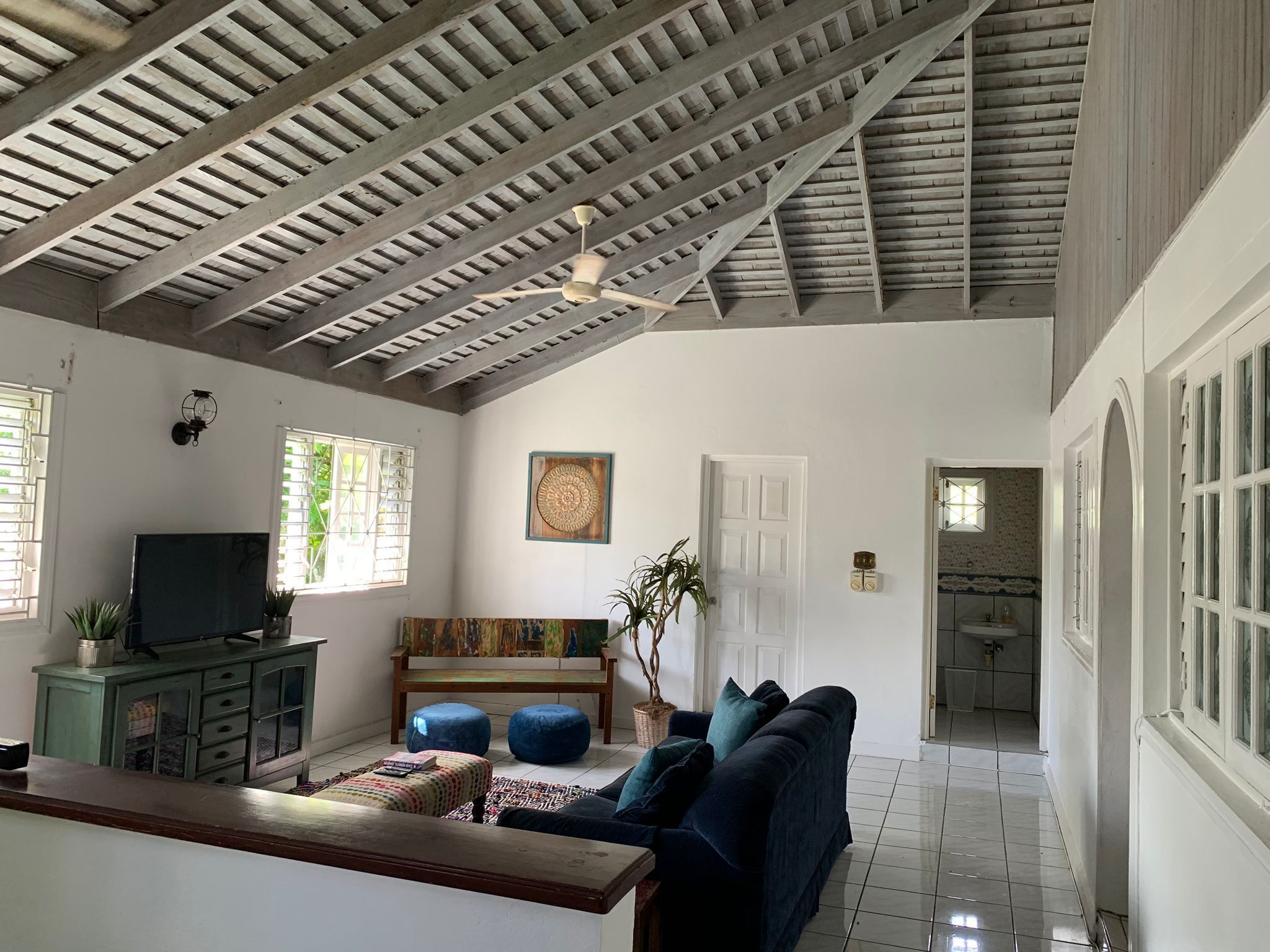 Uma sala de estar espaçosa com pé direito alto, televisão, sofá e área de jantar.