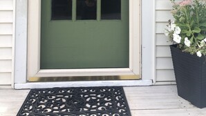 Una puerta verde con un adorno de guirnalda y un cartel de bienvenida.