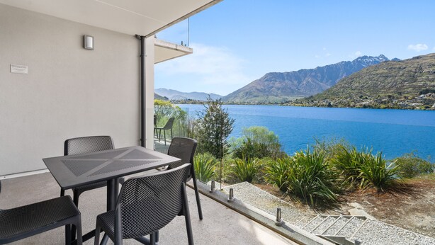 Un balcón con mesa y sillas con vistas a un lago y montañas.