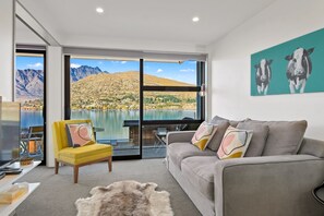 Una sala moderna con sofá, sillón y un cuadro de vacas.