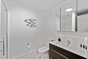 Un baño moderno con inodoro, bidé y tocador con espejo.