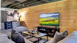 Una sala de estar acogedora con una pared de madera, un televisor de pantalla plana, un sofá y una mesa de centro.