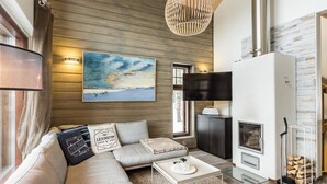 Un salon moderne avec un canapé d’angle, une cheminée et un grand tableau accroché au mur.
