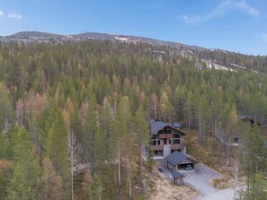 A cabin with a stone exterior, multiple decks, and a driveway leading to a garage.