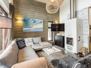 Een moderne woonkamer met een bank, een salontafel, een open haard en een schilderij aan de muur.