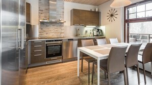 Une cuisine moderne dotée d’un four encastré, d’appareils électroménagers en acier inoxydable et d’un pare-feu en pierre.