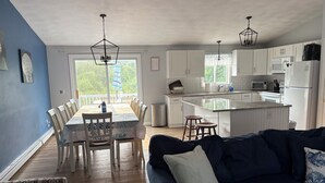 Una cocina moderna con armarios blancos, una isla grande y una zona de comedor con mesa y sillas.