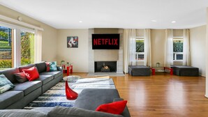 Een moderne woonkamer met een open haard, een grote flatscreen televisie en een zithoek.